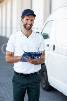 Portrait of delivery man is holding a clipboard and smiling to t