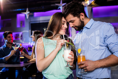 Couple embracing each other at bar counter while having cocktail