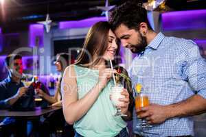 Couple embracing each other at bar counter while having cocktail