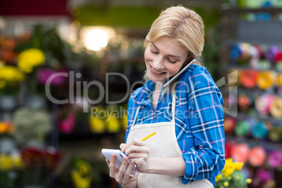 Female florist taking order on mobile phone