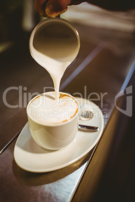 Waiter adding milk to coffee