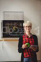 Female graphic designer holding model while using digital tablet