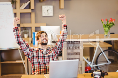 Excited graphic designer sitting with laptop