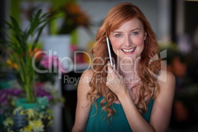 Female florist talking on mobile phone in flower shop