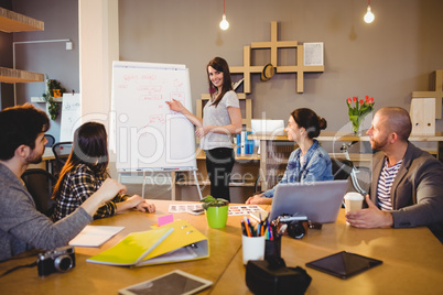 Female graphic designer discussing chart on white board with cow