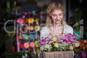 Happy female florist holding basket of flowers