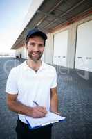 Portrait of delivery man is holding a clipboard and smiling to t