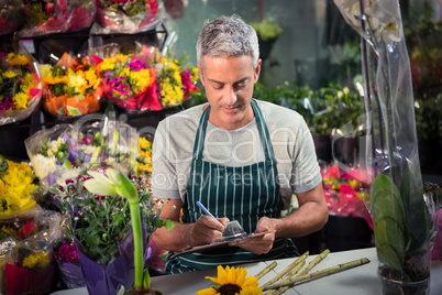 Male florist writing on clipboard