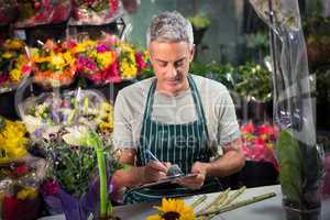 Male florist writing on clipboard