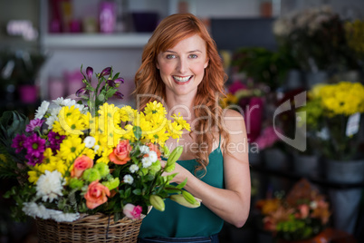 Happy female florist holding basket of flowers