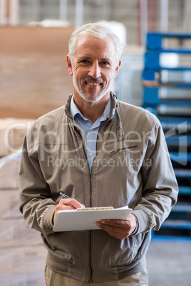 Portrait of manager is holding a clipboard and smiling to the ca