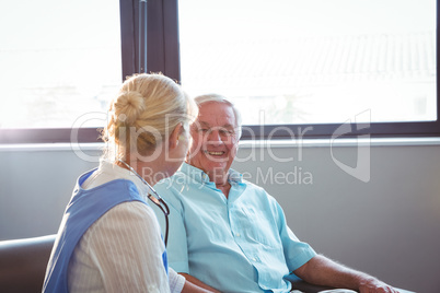 Nurse and senior man sitting on sofa