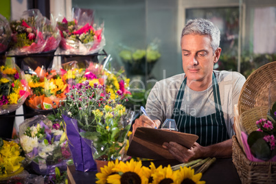 Male florist writing on clipboard