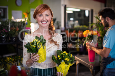 Woman holding flower bouquet while man working in the background