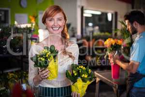 Woman holding flower bouquet while man working in the background