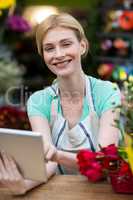 Happy Female florist using digital tablet in florist shop