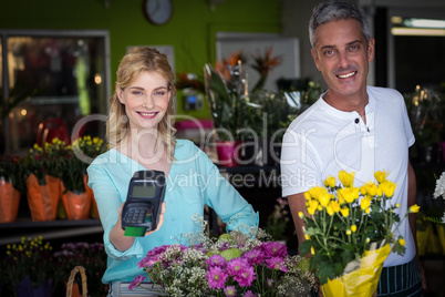 Smiling florist showing credit card terminal in flower shop