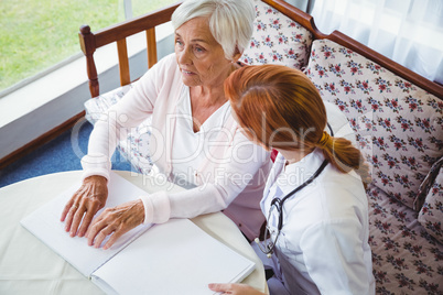 Nurse helping senior woman with braille