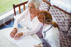 Nurse helping senior woman with braille