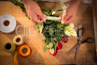 Male florist tying poly ribbon on bunch of flowers