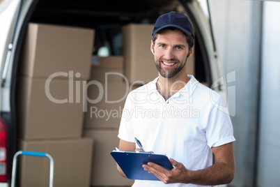 Portrait of delivery man is holding a clipboard and smiling to t