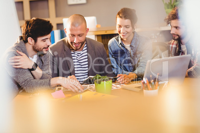 Graphic designer using digital tablet with his coworker