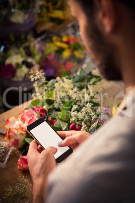 Male florist text messaging on mobile phone