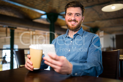 Man holding disposable coffee cup and mobile phone