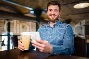 Man holding disposable coffee cup and mobile phone