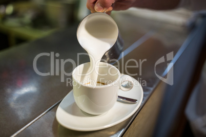 Waiter adding milk to coffee