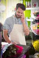 Male florist noting order while talking on mobile phone