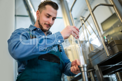 Brewer checking beer with hydrometer