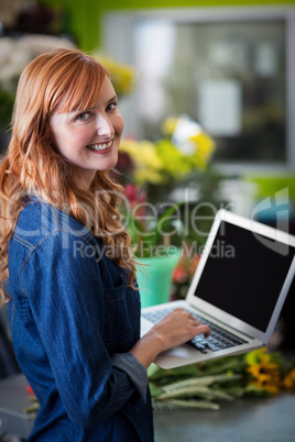 Smiling florist using laptop in flower shop