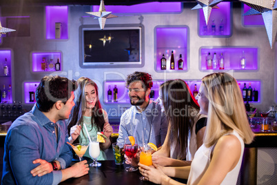 Group of friends interacting with each other at bar counter whil