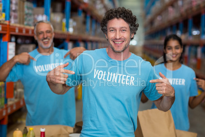 Focus of happy volunteer showing his tee-shirt in front of his t
