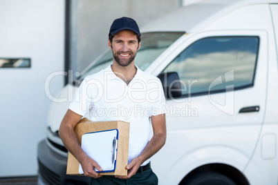 Portrait of delivery man is holding cardboard box and posing