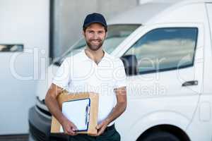 Portrait of delivery man is holding cardboard box and posing