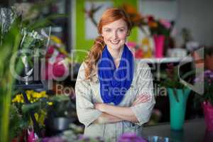 Happy female florist standing with arms crossed in flower shop