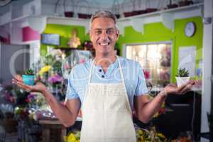 Male florist holding plant pot at flower shop