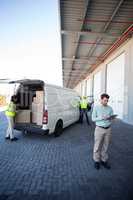 View of manager is using a tablet in front of workers are loadin