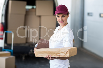 Portrait of delivery woman is holding cardboard box and smiling