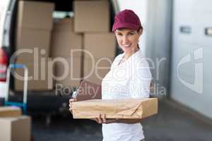 Portrait of delivery woman is holding cardboard box and smiling