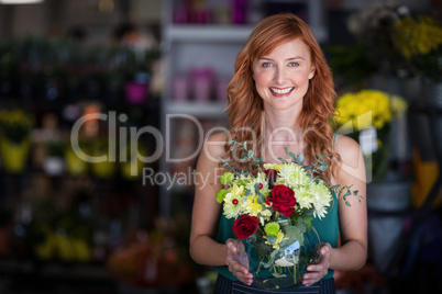 Female florist holding flower vase at flower shop