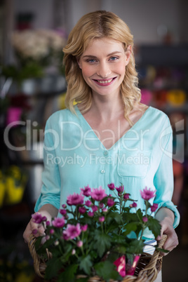 Happy female florist holding basket of flowers