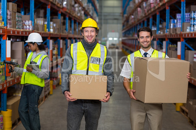Workers looking at camera while holding box