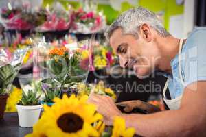 Male florist trimming stems of flowers at flower shop