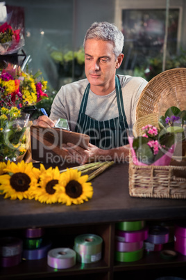 Male florist writing on clipboard