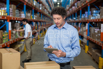 Manager working on a tablet in the middle of cardboard boxes