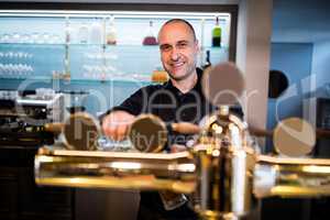 Brewer filling beer in beer glass from beer pump