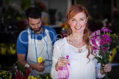 Woman holding bunch of flowers while man preparing flower bouque